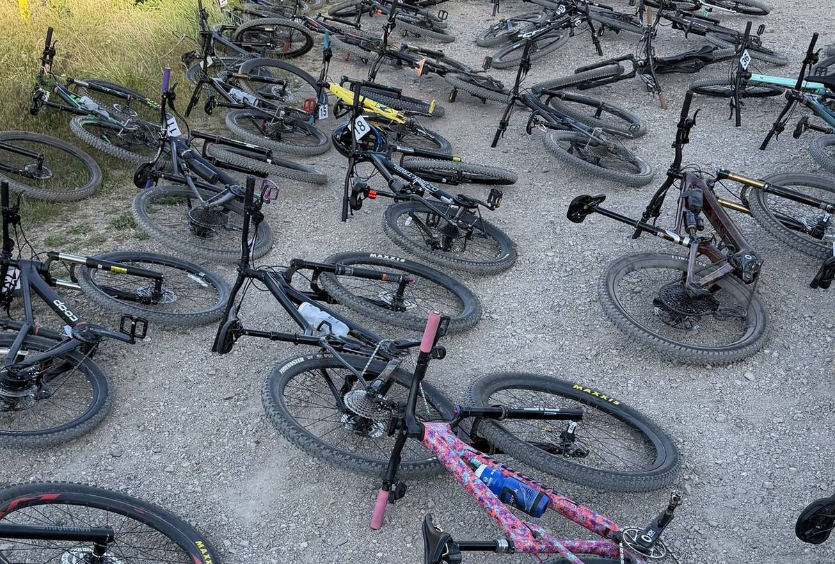 Dozens of mountain bikes laid on the gravel at a trailhead during team practice
